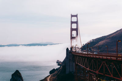 Golden gate bridge over bay against cloudy sky