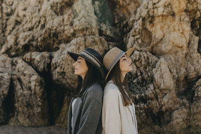 Young sisters back to back by rock formation