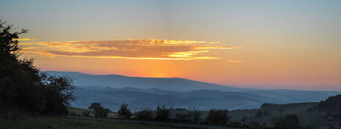 Scenic view of silhouette mountains against orange sky