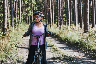 Active woman cycling on forest road. female riding bicycle off-road route on summer vacation day