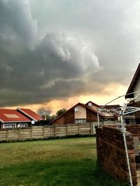 Houses on field against cloudy sky