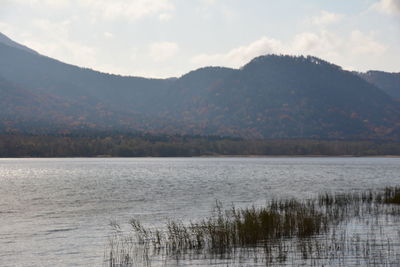 Scenic view of lake by mountains against sky