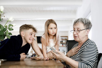 Grandmother and grandchildren using cell phone at home