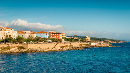 Houses at waterfront against blue sky