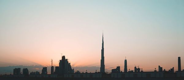 Silhouette of city against sky during sunset