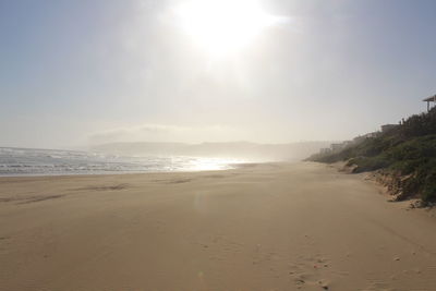 Scenic view of beach against sky on sunny day