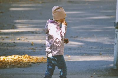 Side view of girl walking on footpath during autumn