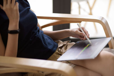 Midsection of woman using digital tablet