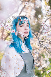 Portrait of woman with pink flowers against trees