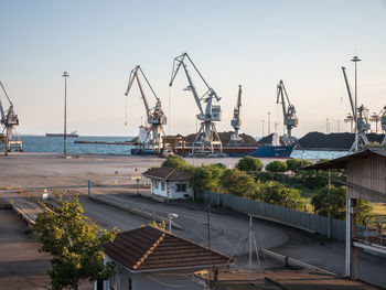 Cranes at harbor against sky