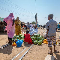 Rear view of people at market stall against clear sky