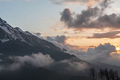 Mountain view of snow capped peaks of caucasus mountains in clouds at sunset, beautiful landscape