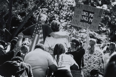 Rear view of people on street against trees