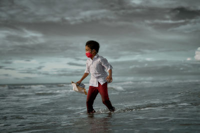 Full length of man standing on beach against sky