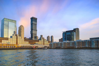 Modern buildings by river against sky in city