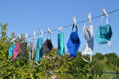 A lot of different colorful self made corona face masks out of fabric hanging on clothesline drying