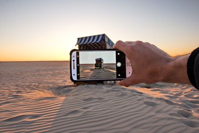 Close-up of man photographing on sand at beach