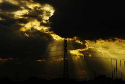 Low angle view of electricity pylon against cloudy sky