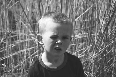 Portrait of cute boy winking eye while standing on grassy field