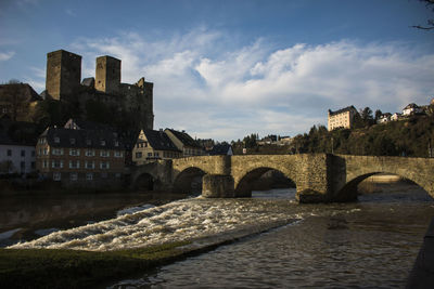 Arch bridge over river by buildings