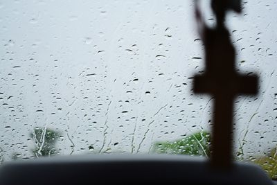 Close-up of wet window against sky