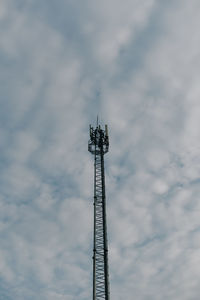 Low angle view of communications tower against cloudy sky