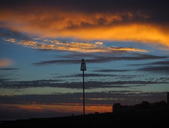 Silhouette bird perching on pole against sky during sunset