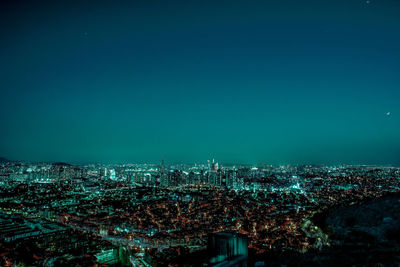 Cityscape against clear blue sky at night