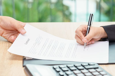 Cropped image of man holding book with text on table