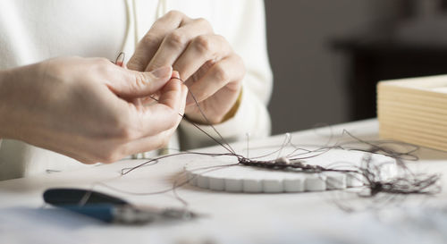 Close-up of woman working with thread on table