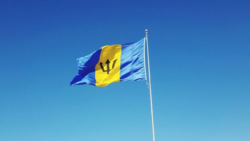 Low angle view of barbados flag against clear blue sky