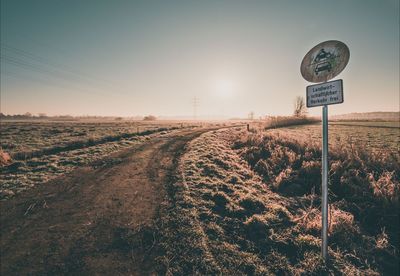 Road sign on land against sky