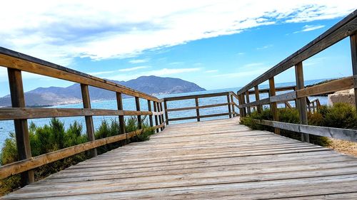 Footbridge over lake against sky