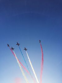 Low angle view of airshow against clear blue sky