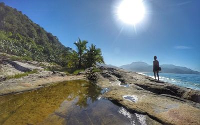 Man standing on rock against sky