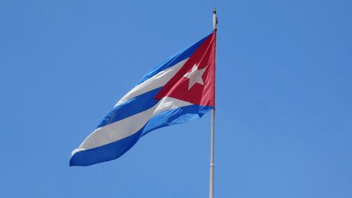 Low angle view of cuban flag against clear blue sky