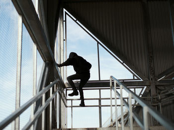 Low angle view of man on railing against building
