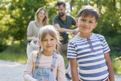 Portrait of happy friends standing against trees