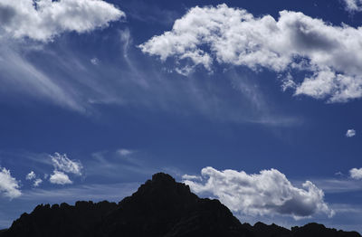 Low angle view of silhouette mountains against blue sky