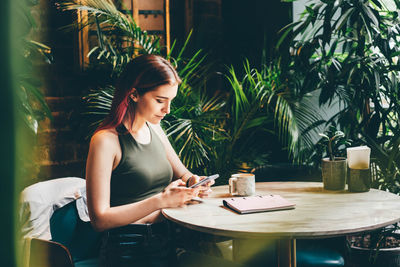 Woman reading good news on mobile phone during rest in coffee shop.