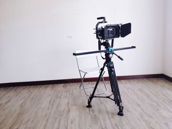 Tripod camera on floor against wall in room