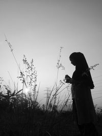 Side view of silhouette woman standing on field against sky