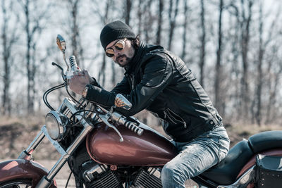 Mid adult man sitting on motorcycle in forest