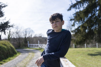 Young teenager male leaning on countryside fence looking camera