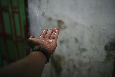 Cropped image of person hand on wet wall