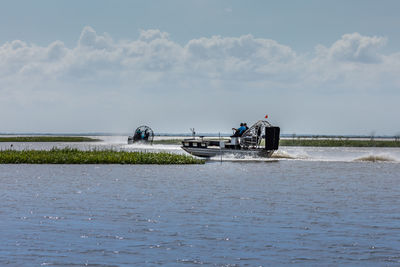 People on boat in sea against sky