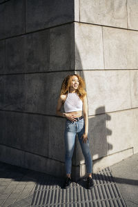 Full length portrait of woman against wall