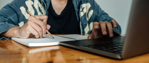Midsection of businesswoman using laptop on table