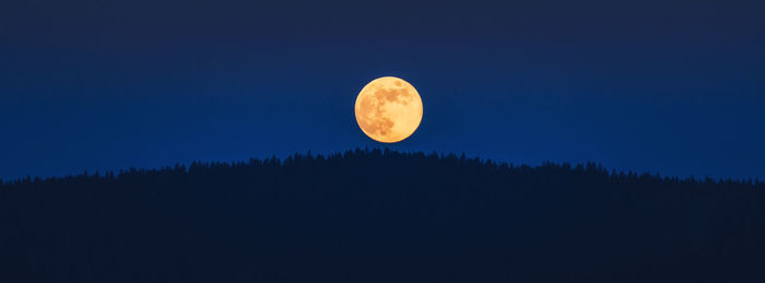 Low angle view of moon against clear blue sky at night