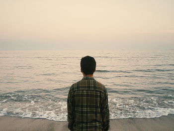 Rear view of man standing against sea